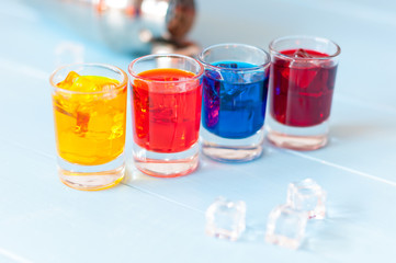 Set of alcoholic cocktails with metal shaker on white bar