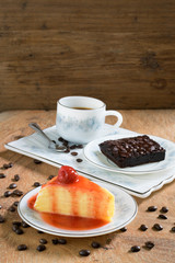 Crepe cake, brownie and a cup of coffee on wooden background