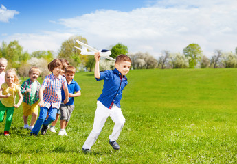 Kids running and boy holding white airplane toy