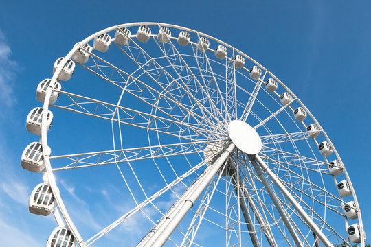 modern white ferris wheel against blue sky background