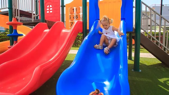 little girl with hairtails slides down on playground	