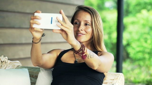 Young woman taking selfie with cellphone on sofa on terrace
