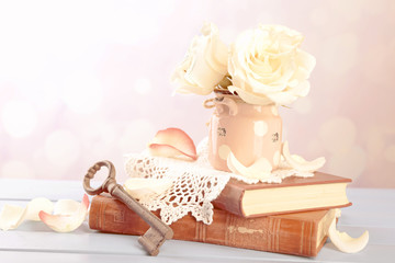 Fototapeta na wymiar Fresh roses with old book and letters on color wooden table, on light background. Vintage concept