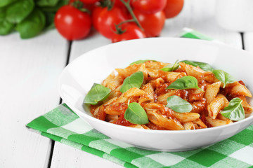 Pasta with tomato sauce and basil on table close up
