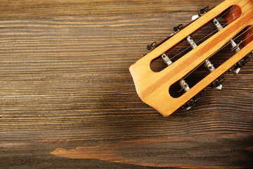 Neck of acoustic guitar on wooden background