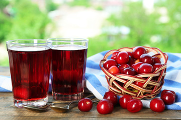 Glasses of sweet homemade cherry compote on table on bright background