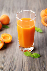 Glass of apricot juice and fresh fruits on table close up