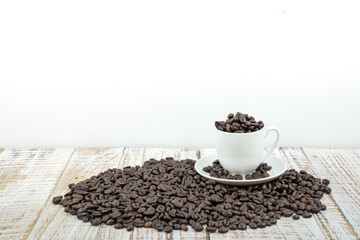 Coffee cup with roasted coffee beans on wooden table