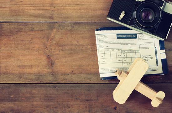 image of flying ticket wooden airplane and passport over wooden table. retro filtered image
