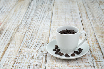 Coffee cup with roasted coffee beans on wooden table