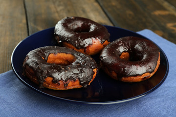 Delicious doughnuts with chocolate icing on table close up