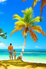 father and son standing on tropical island beach