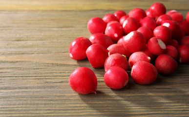 Heap of fresh radishes on wooden table close up background