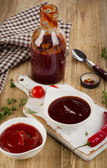 Bowls of tomato and bbq sauce on  a old wooden table.