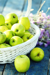 Green apples with bouquet of wildflowers on wooden table, closeup