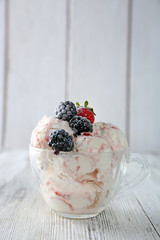 Delicious ice cream with fresh frozen berries, on color wooden background