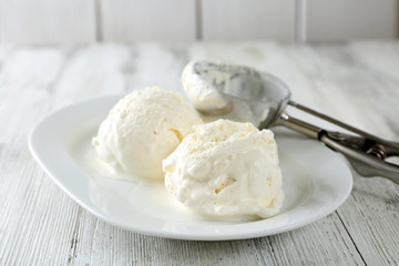 Delicious vanilla ice cream on plate, on wooden background
