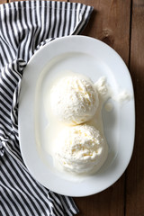 Delicious vanilla ice cream on plate, on wooden background