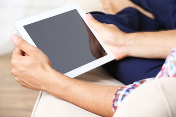 Male hand holding PC tablet on home interior background