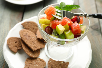 Fruit salad in glass bowl, on wooden background