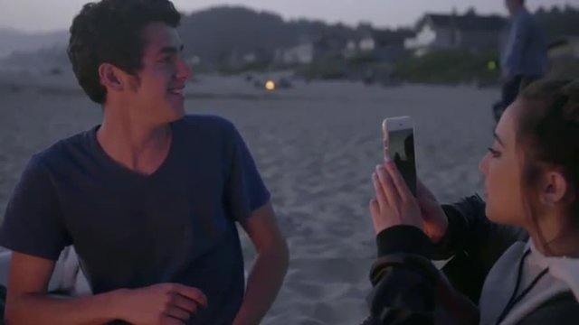 Cute teenage girl takes picture of her friends at the beach