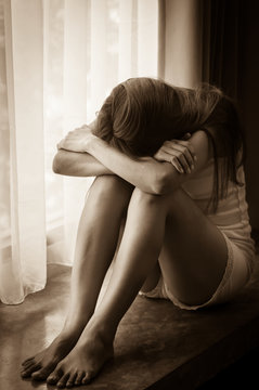 Sad girl sitting near window