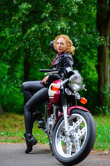 Fototapeta na wymiar Biker girl in leather jacket on a motorcycle