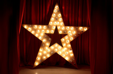 Photo of golden star with light bulbs on red velvet curtain on stage - obrazy, fototapety, plakaty