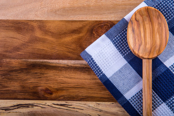 Two wooden cooking spoons on blue towel on wooden table.