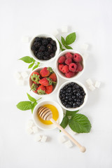 Honey and berries on white background