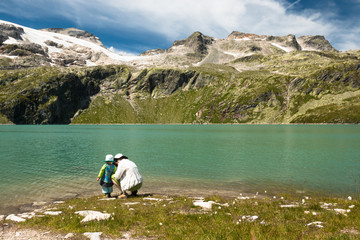mother with child relaxing near glacier lake in austrian alps