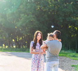 Happy Young Family Walking In The Park.