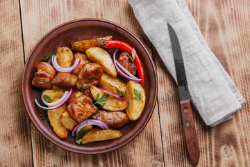 baked fried potatoes with meat  plate on  wooden surface