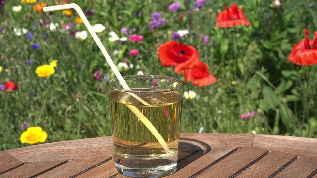Apple  juice on table in the garden in front of summer flowers