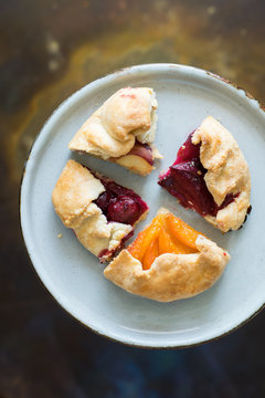 Assortment of four homemade pies pieces with pluots, apricots, sour cherries and peaches on the plate