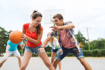 group of happy teenagers playing basketball