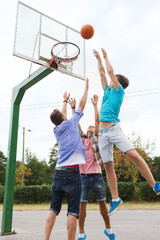 group of happy teenage friends playing basketball