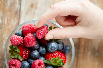 close up of woman hands with berries in glass bowl
