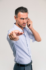 Businessman talking on the phone and pointing at camera