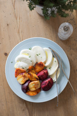 Starter of italian mozzarella cheese and grilled pluots, apricots and flat peaches with olive oil and thyme on the wooden background