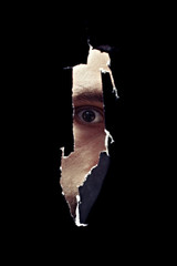 Scary eye of a man spying through a hole in the wall