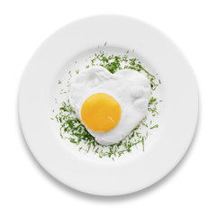 Heart-shaped fried egg with herbs on a white plate isolated.