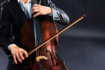 Man playing on cello on dark background