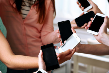 Many hands holding mobile phones close up