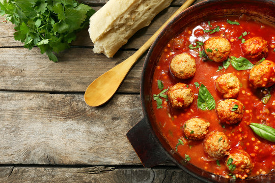 Pan with meat balls in tomato sauce, on wooden background