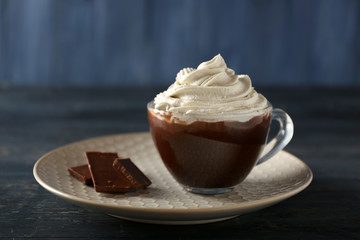 Cup of coffee with cream on color wooden background