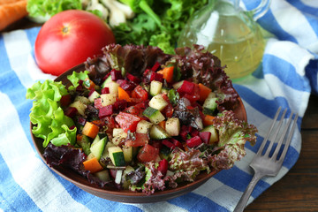 Wooden bowl of fresh vegetable salad on table, closeup