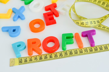 measure your profit concept written as magnetic colored  letter blocks with scale 



