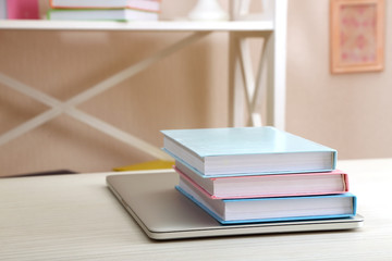 Stack of books with laptop on table in room