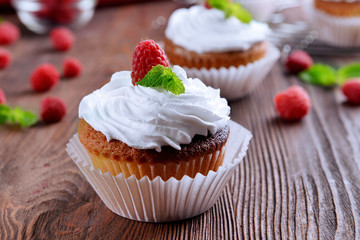 Delicious cupcakes with berries and fresh mint on wooden table close up